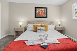 Una habitación de hotel con una cama, dos mesitas de noche, un cuadro enmarco y una colcha roja.