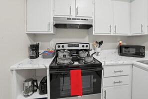 A kitchen with a stove, microwave, and cabinets. - Eastdale Modern Marvel (Montgomery)