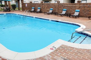 Ein Pool mit Ziegelbord und Liegestühlen.