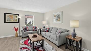 A living room with a grey sofa, a wooden coffee table, and two side tables with lamps.