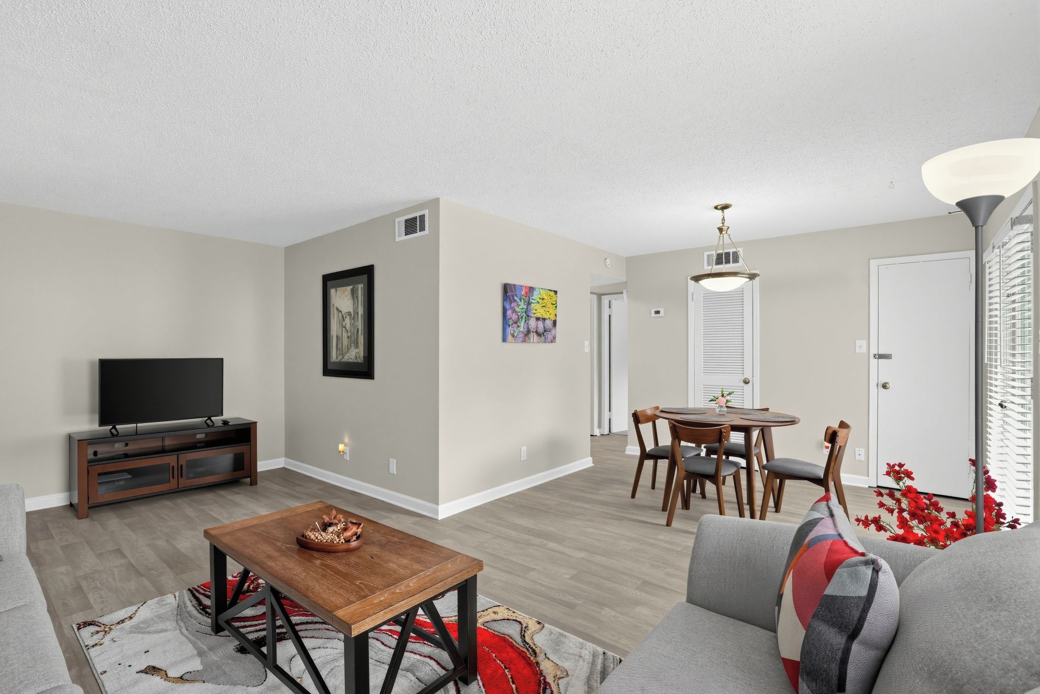 A living room with a sofa, a coffee table, a TV, and a dining area with chairs and a table.