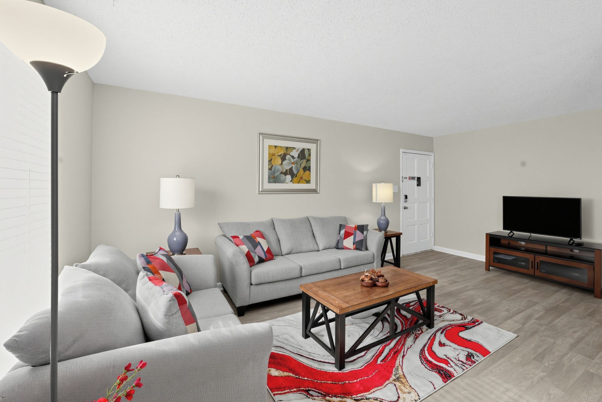 A living room with a sofa, a coffee table, a TV, and a painting on the wall.