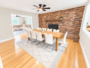 A dining area with a brick wall, a ceiling fan, and a fireplace. - Family Pet friendly Private 11-Acre Country Retreat with 6 bedrooms & Disc Golf (Griffin)