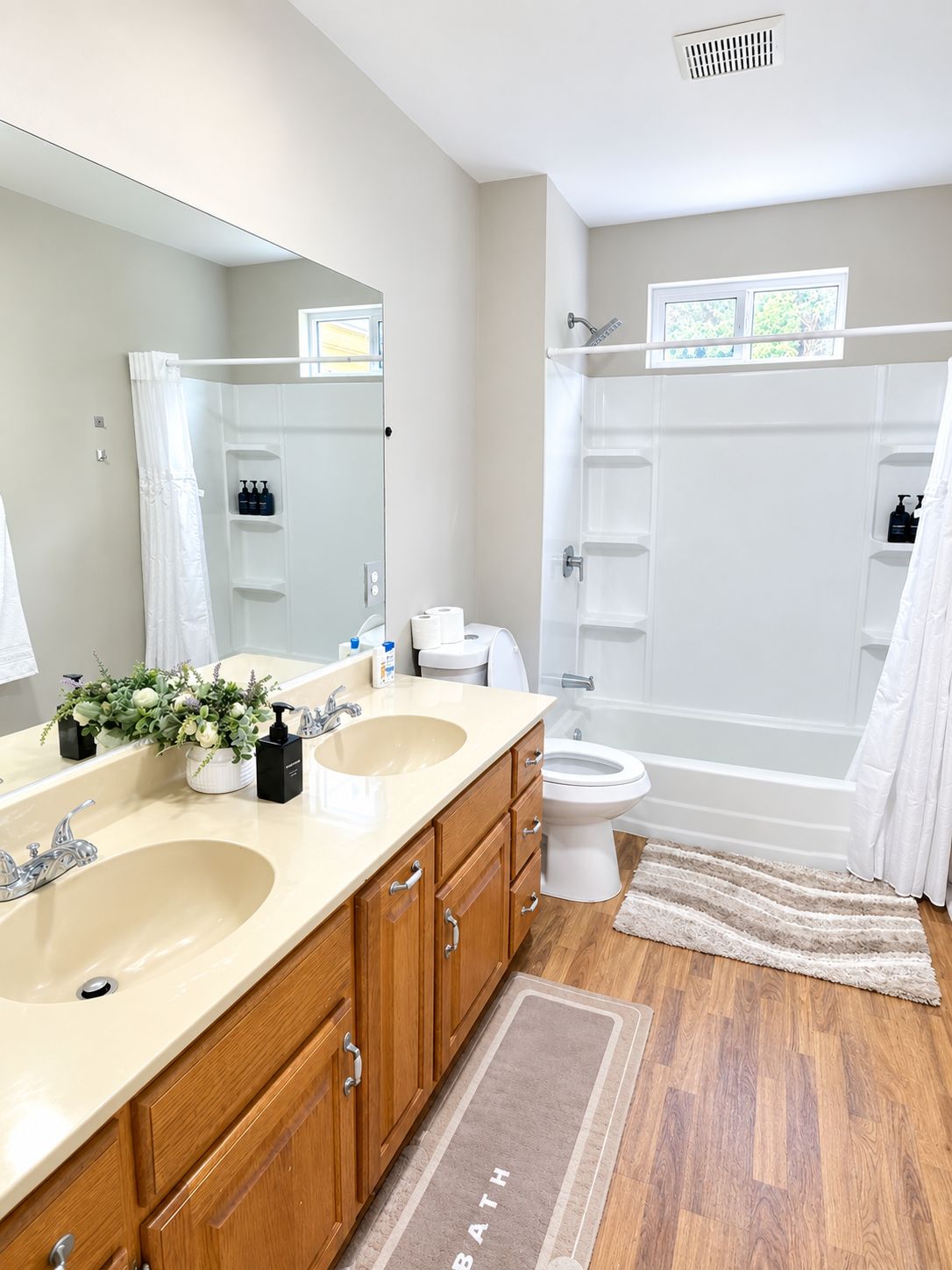 Une salle de bain moderne avec deux vasques, un grand miroir, une douche et des toilettes.