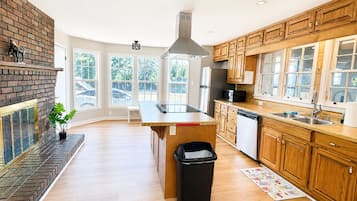 Une cuisine moderne avec des meubles en bois, un îlot central et une cheminée en briques.