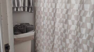 A bathroom with a toilet, a towel rack with striped towels, and a geometric patterned shower curtain.