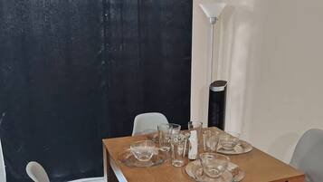 A dining area with a wooden table set for four, surrounded by white chairs.