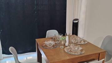 A dining area with a wooden table set for four, surrounded by four chairs.
