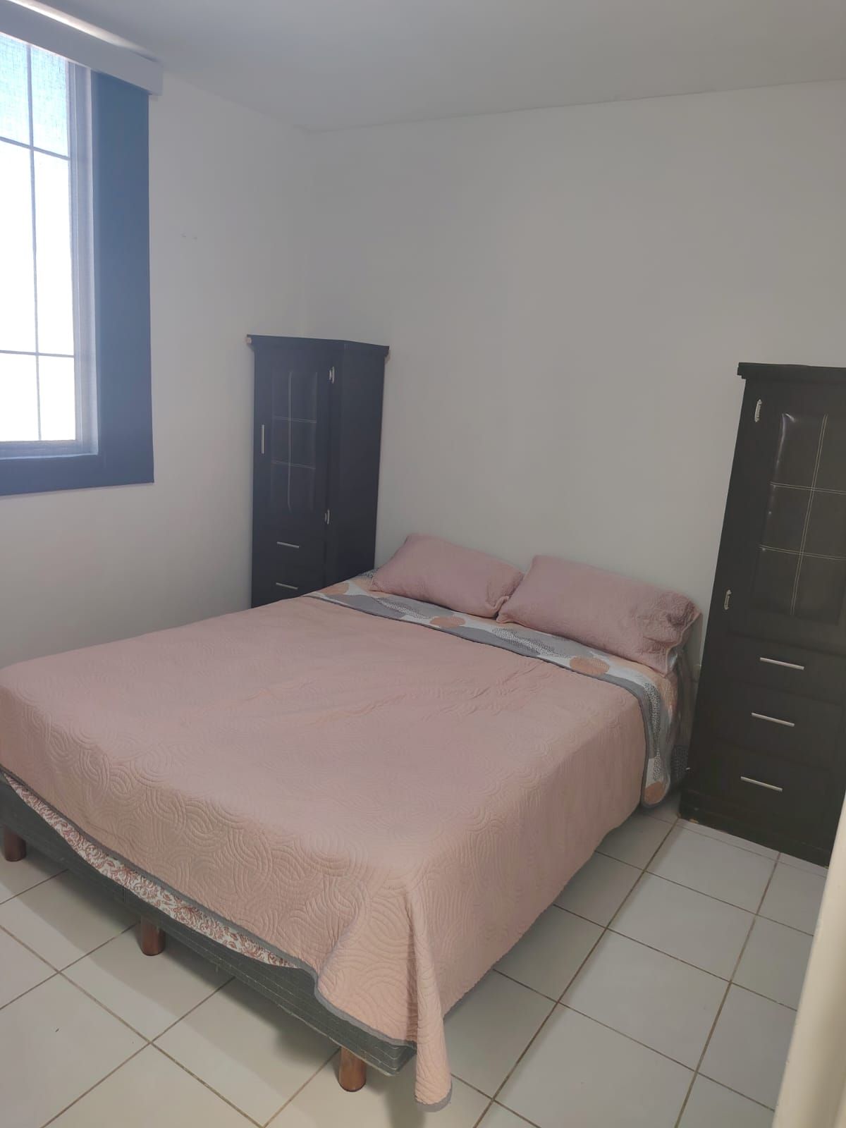 A bedroom with a bed, a wardrobe, and a window.