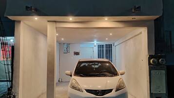 A white car parked inside a garage with a white door and a small window.