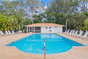 A pool with lounge chairs and a building with a tiled roof. - Bay Forest 3BR | Preserve Views (Naples)