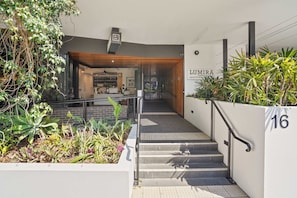 Escadaria que leva a uma entrada com a placa 'LUMIRA apartments' e o número '16' na parede.