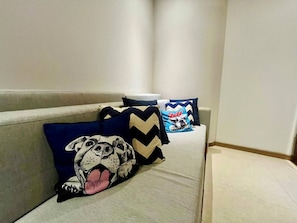 A sofa with multiple pillows, including a dog-themed pillow and a chevron-patterned pillow. - Hermoso Depto. en Playa Peninsula Nuevo Vallarta (Nuevo Vallarta)