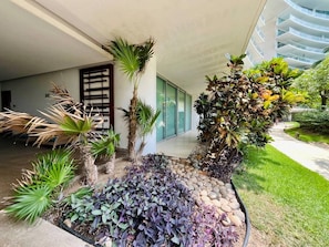 A landscaped outdoor area with various plants and a pathway leading to a building entrance. - Hermoso Depto. en Playa Peninsula Nuevo Vallarta (Nuevo Vallarta)