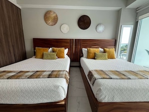A hotel room with two beds, a wooden headboard, decorative wall art, and a view through a window. - Maritima Playa Nvo Vallarta Elegante 3Rec/8p/Gym (Bucerías)