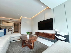 A modern living room with a flat-screen TV, a round wooden coffee table, a sofa, and a dining area. - Maritima Playa Nvo Vallarta Elegante 3Rec/8p/Gym (Bucerías)