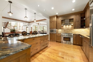 A modern kitchen with wooden cabinets, a central island, stainless steel appliances, and pendant lighting. - Spruce Slopeside Ski-in Access (Beaver Creek)