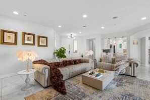 A spacious living room with a large sofa, a coffee table, and a patterned rug. - Luxury Escape | Heated Pool/Spa • Views + Events (Alpine)
