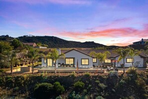 A modern residential area with multiple houses, a clear sky, and a hilly landscape in the background. - Luxury Escape | Heated Pool/Spa • Views + Events (Alpine)