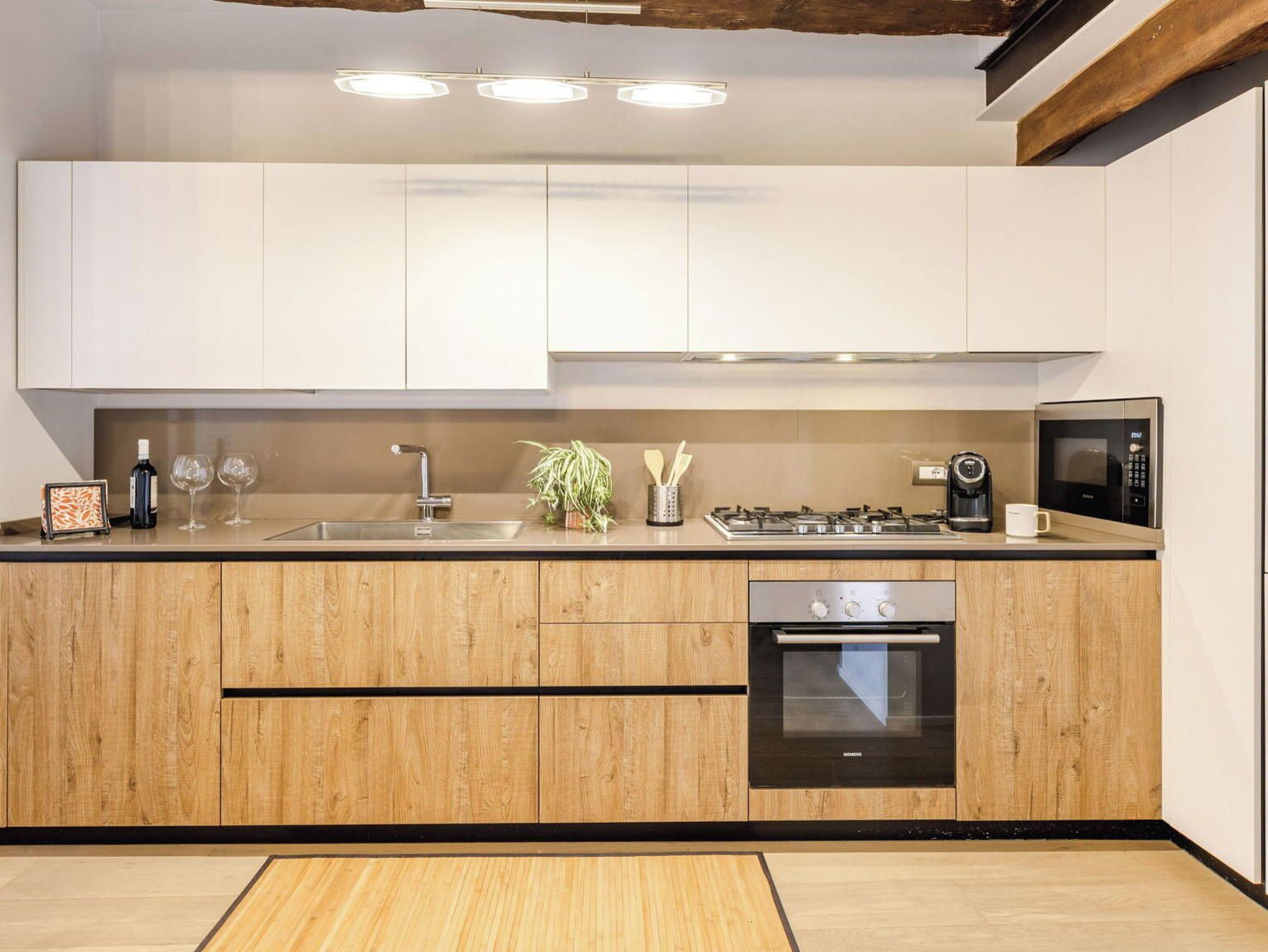 A modern kitchen with wooden cabinetry, a stainless steel sink, a built-in oven, and a microwave.