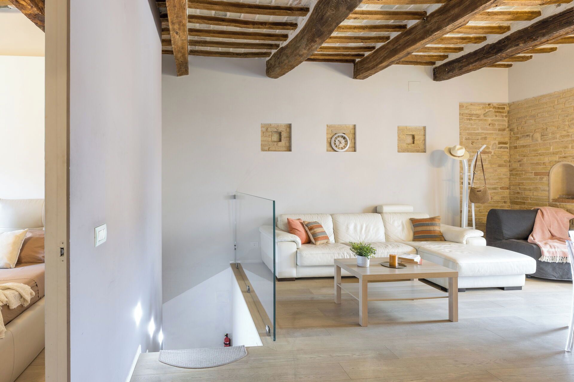 A modern living room with a white sofa, a wooden coffee table, and a stone wall.