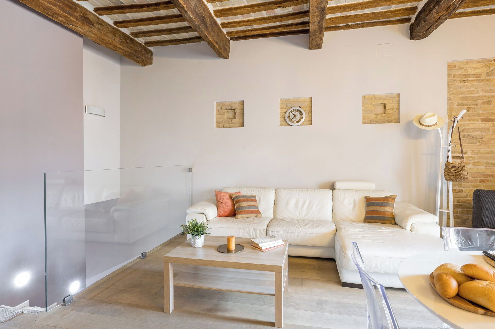 A modern living room with a white sofa, a wooden coffee table, and a glass door.