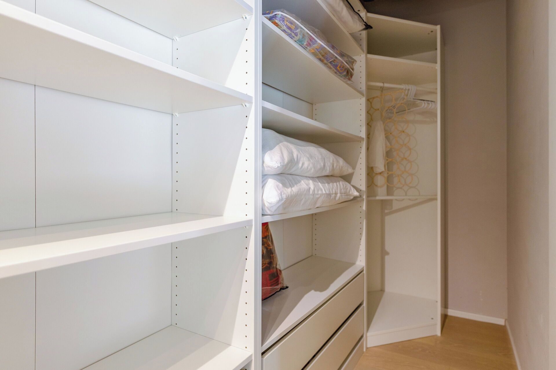 A closet with multiple shelves and drawers, some containing folded items.