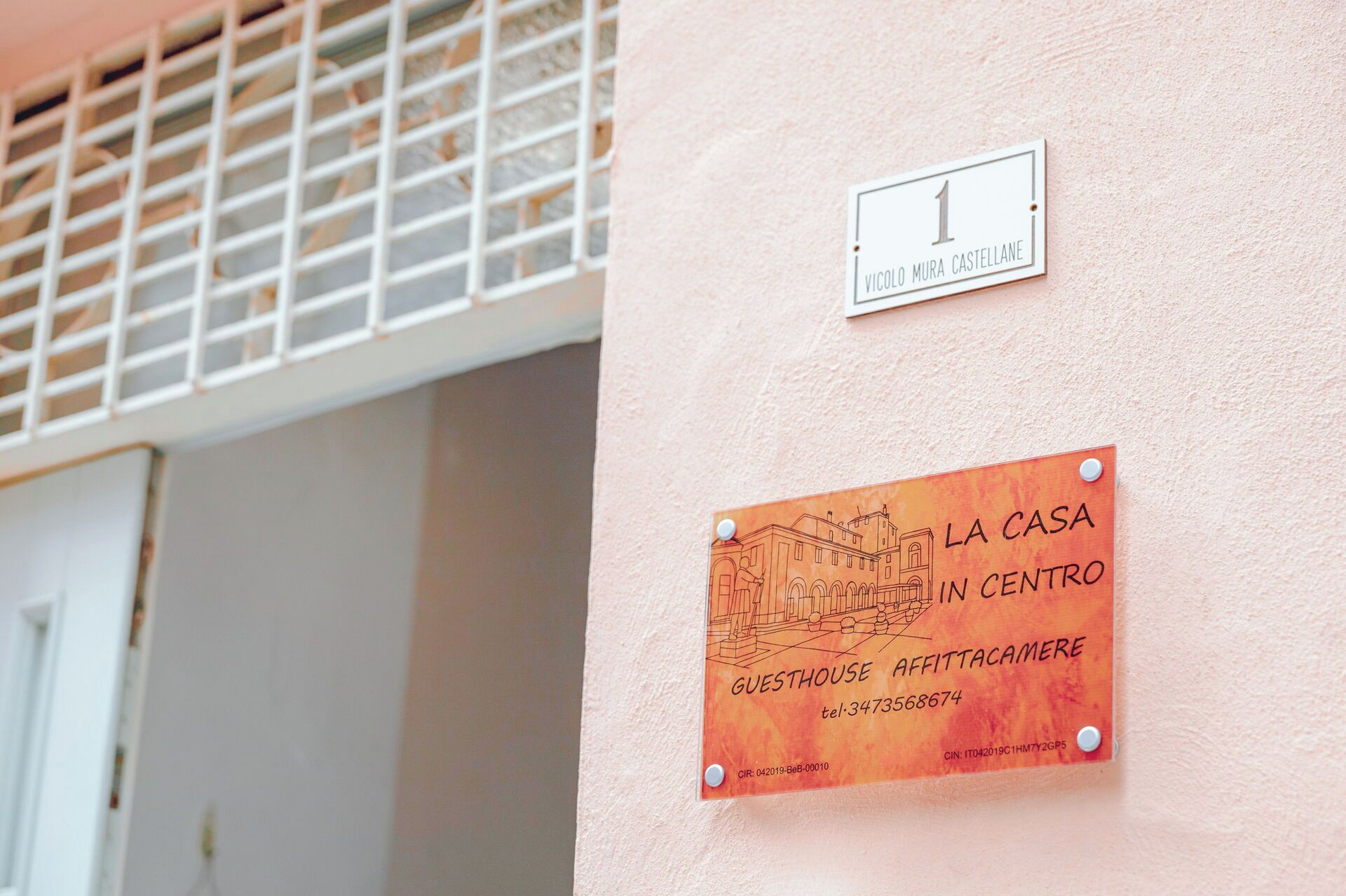 A wall with two signs: one indicating room number 1 and another for a guesthouse named 'La Casa in Centro' with contact information.