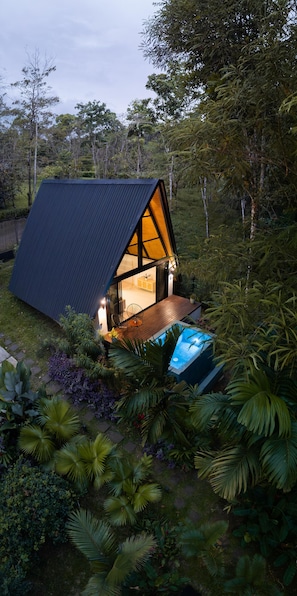 Une maison moderne, de forme triangulaire, dotée d’une terrasse en bois et d’une piscine.