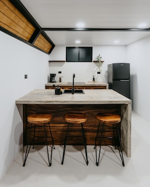 Une cuisine dotée d’un îlot central, de tabourets de bar, d’un réfrigérateur noir et d’un plafond en bois.