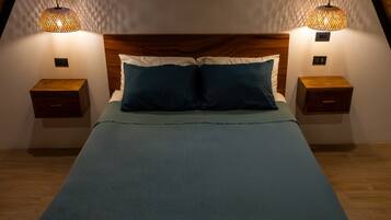 Une chambre à coucher avec une tête de lit en bois, deux tables de chevet et un lit recouvert d’une couverture bleue.