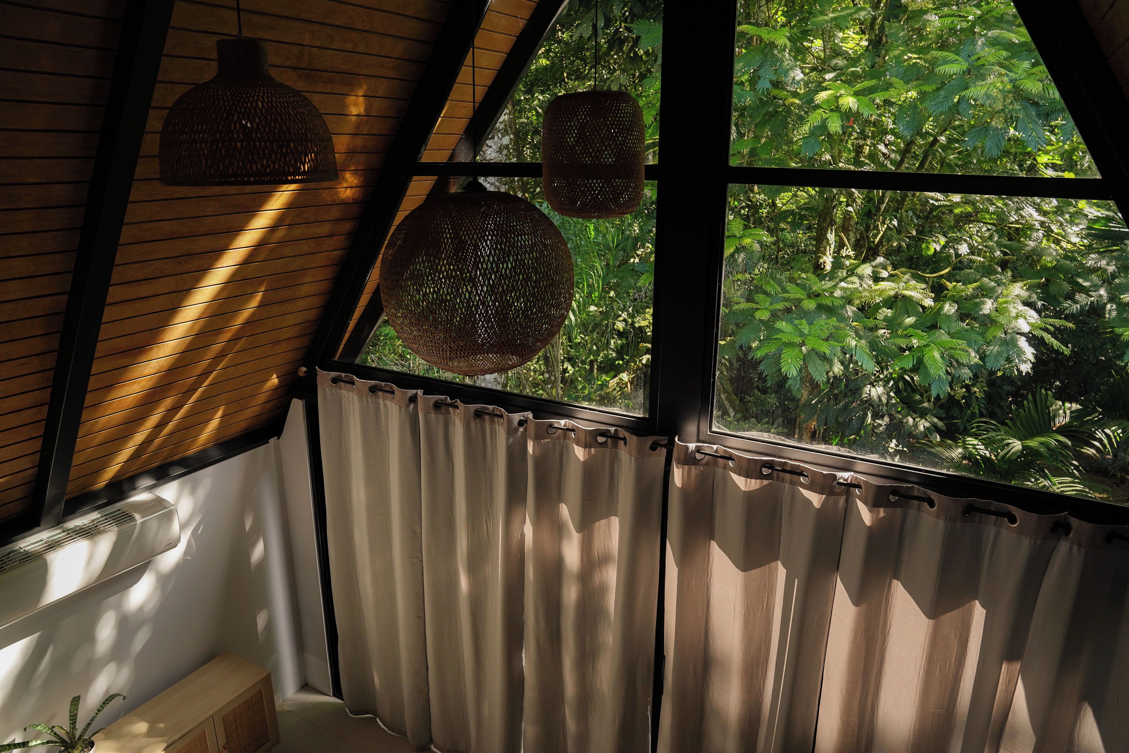Une pièce dotée d’une grande fenêtre, de lambris en bois au mur et d’un rideau.