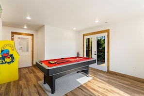 Mesa de bilhar em um ambiente com piso de madeira e paredes brancas.
