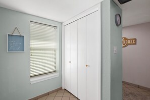 A hallway with a closed door, a window with blinds, a wall clock, and a sign that reads 'HOUSE'. - Saida III #606 | Beachfront Condo • 3 Pools • Tennis & Pickleball (South Padre Island)