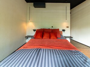 A modern bedroom with a large bed, two bedside tables, and a wall-mounted heater. - The Blooming Refuge - Hydrangea Cabin (La Roche-en-Ardenne)