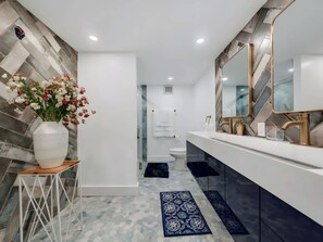 A modern bathroom with a white vanity, a large mirror, and a decorative vase with flowers. - Two-Story 3BR with Pool Table and Private Yard (St. Petersburg)