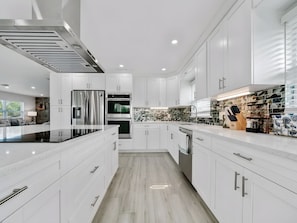 A modern kitchen with white cabinetry, stainless steel appliances, and a central island. - Two-Story 3BR with Pool Table and Private Yard (St. Petersburg)