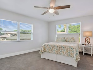 A bedroom with a bed, a ceiling fan, a nightstand, a lamp, and two windows with blinds. - Two-Story 3BR with Pool Table and Private Yard (St. Petersburg)