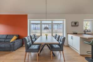 Eine moderne Küche mit Essbereich, ausgestattet mit einem großen Tisch, Stühlen und einer Pendelleuchte.