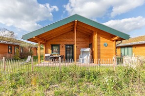 Eine Holzhütte mit überdachter Terrasse, einem Esstisch und einem Stuhl.