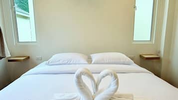 A hotel room with a bed, two bedside tables, a wall-mounted light, and two windows.
