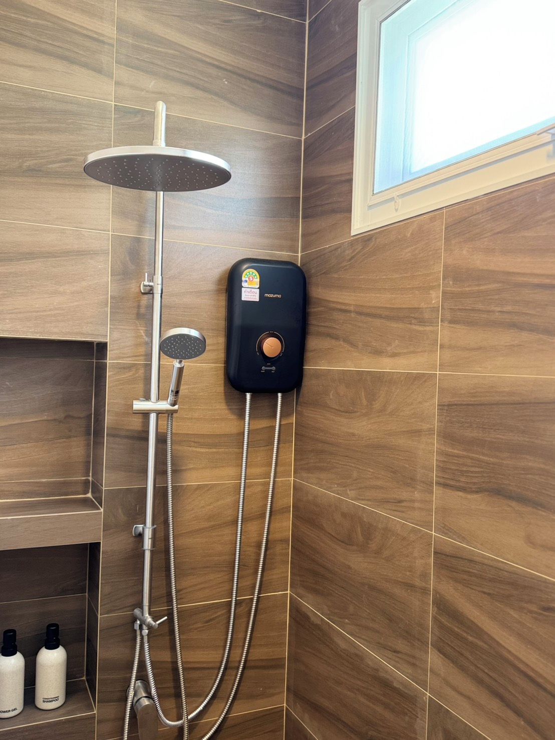 A shower with a handheld showerhead, a wall-mounted control panel, and a handheld shower attachment.