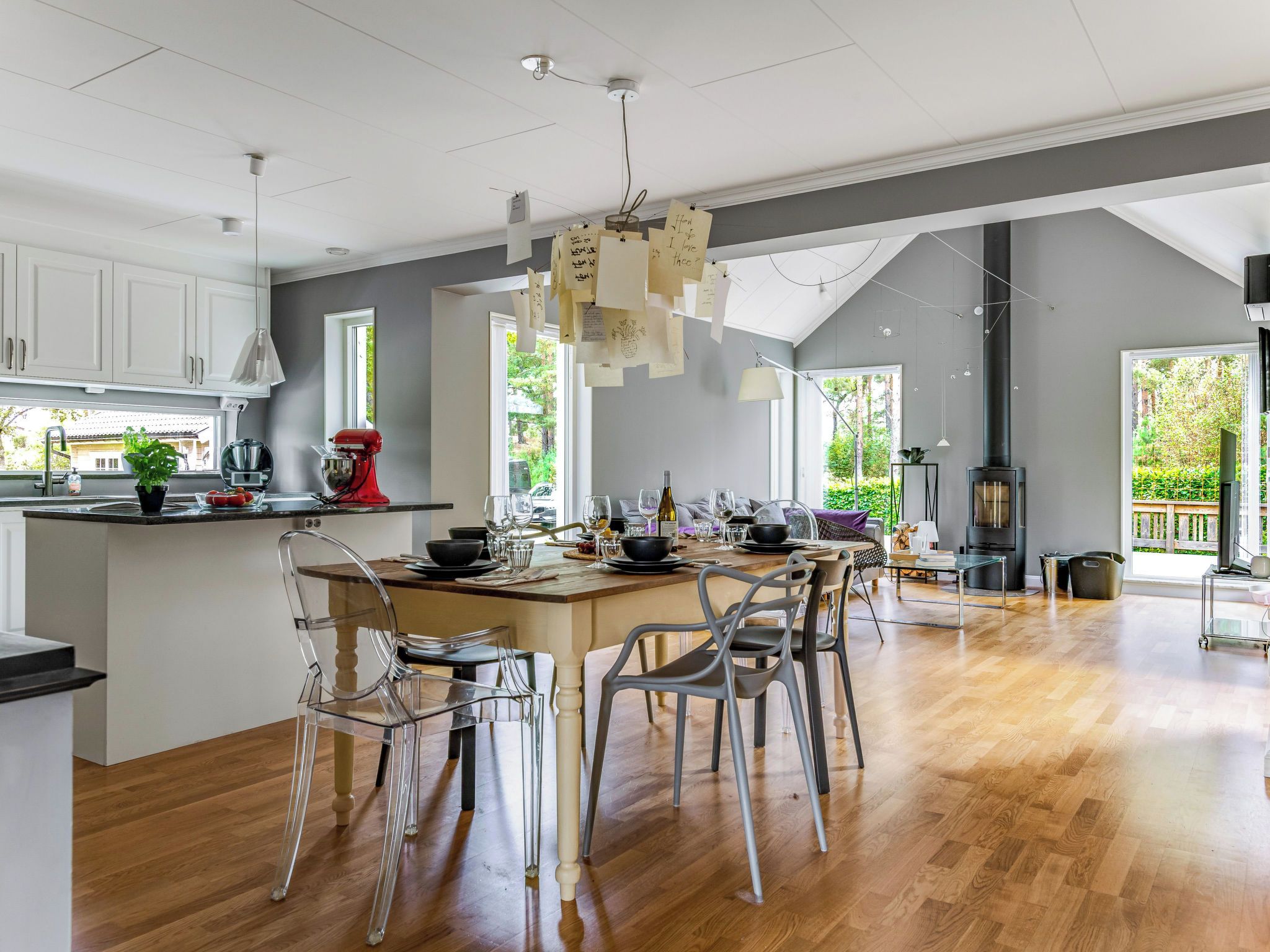Una cocina moderna con una isla central, sillas traslúcidas y una mesa de comedor dispuesta para seis comensales.