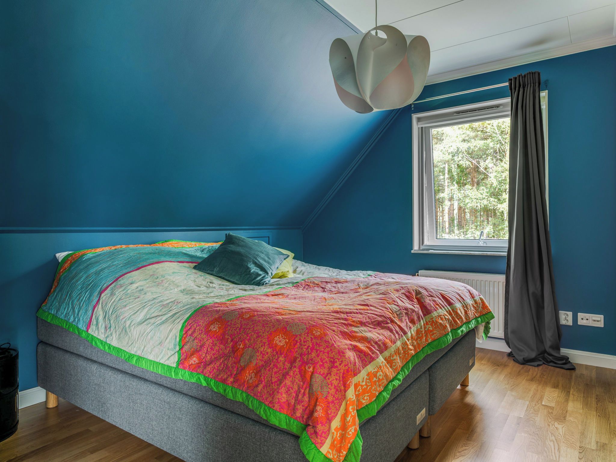 Un dormitorio con una cama, una ventana con cortinas y una lámpara en el techo.