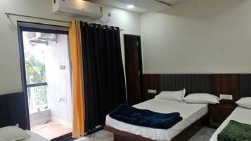 A hotel room with two beds, a ceiling fan, and an air conditioning unit.