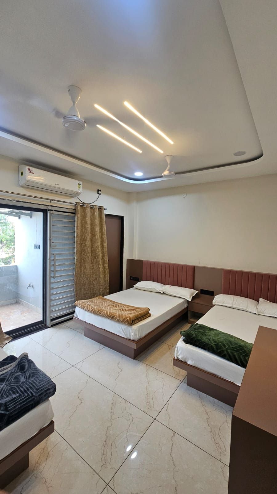 A hotel room with two beds, a ceiling fan, an air conditioning unit, and a sliding glass door leading to an outdoor area.