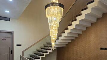 Un escalier moderne avec une rampe en verre, un lustre et un plancher poli.