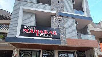 Un hôtel appelé « MAHAKAL PALACE », doté d’une façade moderne, d’un balcon et d’une enseigne.