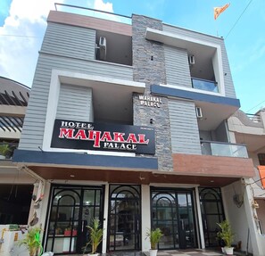 Um hotel chamado 'MAHAKAL PALACE' com fachada moderna, uma varanda e uma placa.