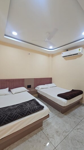 A hotel room with two beds, a ceiling fan, an air conditioning unit, and tiled flooring. - Hotel Mahakal Palace (Ujjain)